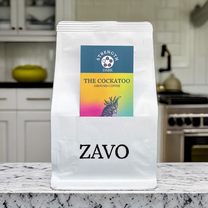 A white coffee bag with a black ZAVO logo stamped at the bottom of the bag, two product cards are visible for the Blend which is the Cockatoo and the Tasting Notes, the image is shot on a marble kitchen work surface with a blurred image of a kitchen behind the product.