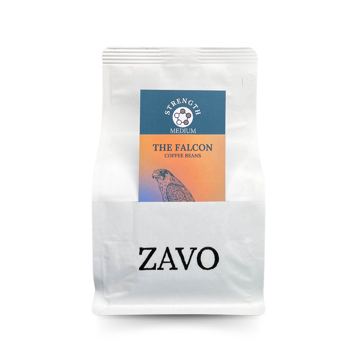 A white coffee bag with two description cards, the first one is multicoloured with a Falcon on it and the second says Strength Medium for the coffee card, the black logo for ZAVO is visible at the bottom of the bag. This coffee bag is on a white background.