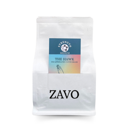 A white coffee bag with a black ZAVO logo stamped on. It has two product cards, one is a blue and red multicoloured card with a Hawk on, the other is a blue tasting notes card which says Strength Medium