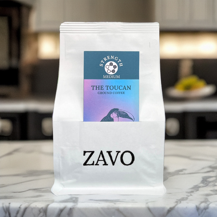 A white coffee bag with a black ZAVO logo stamped at the bottom of the bag, two product cards are visible for the blend which is the Toucan and the tasting notes, the image is shot on a marble work surface in a kitchen 