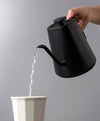 A black temperature control electric kettle pouring water in to a white mug